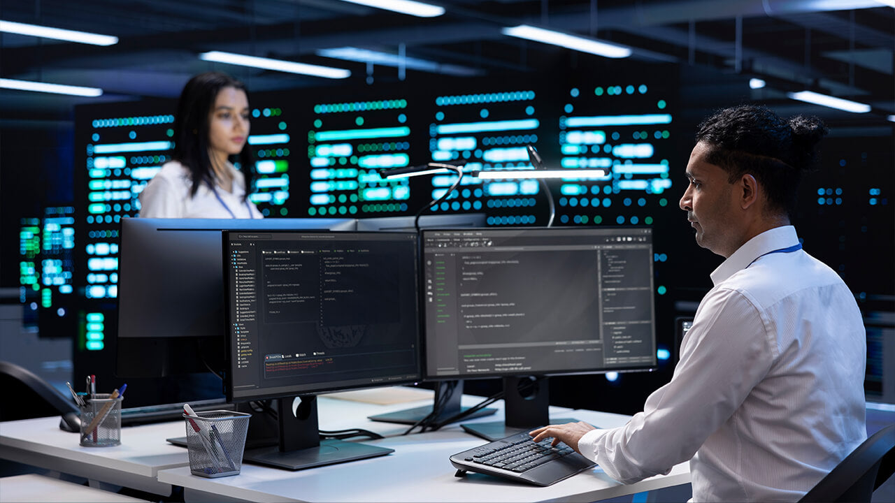 Team IT davanti a postazioni di sviluppo con sala server sullo sfondo